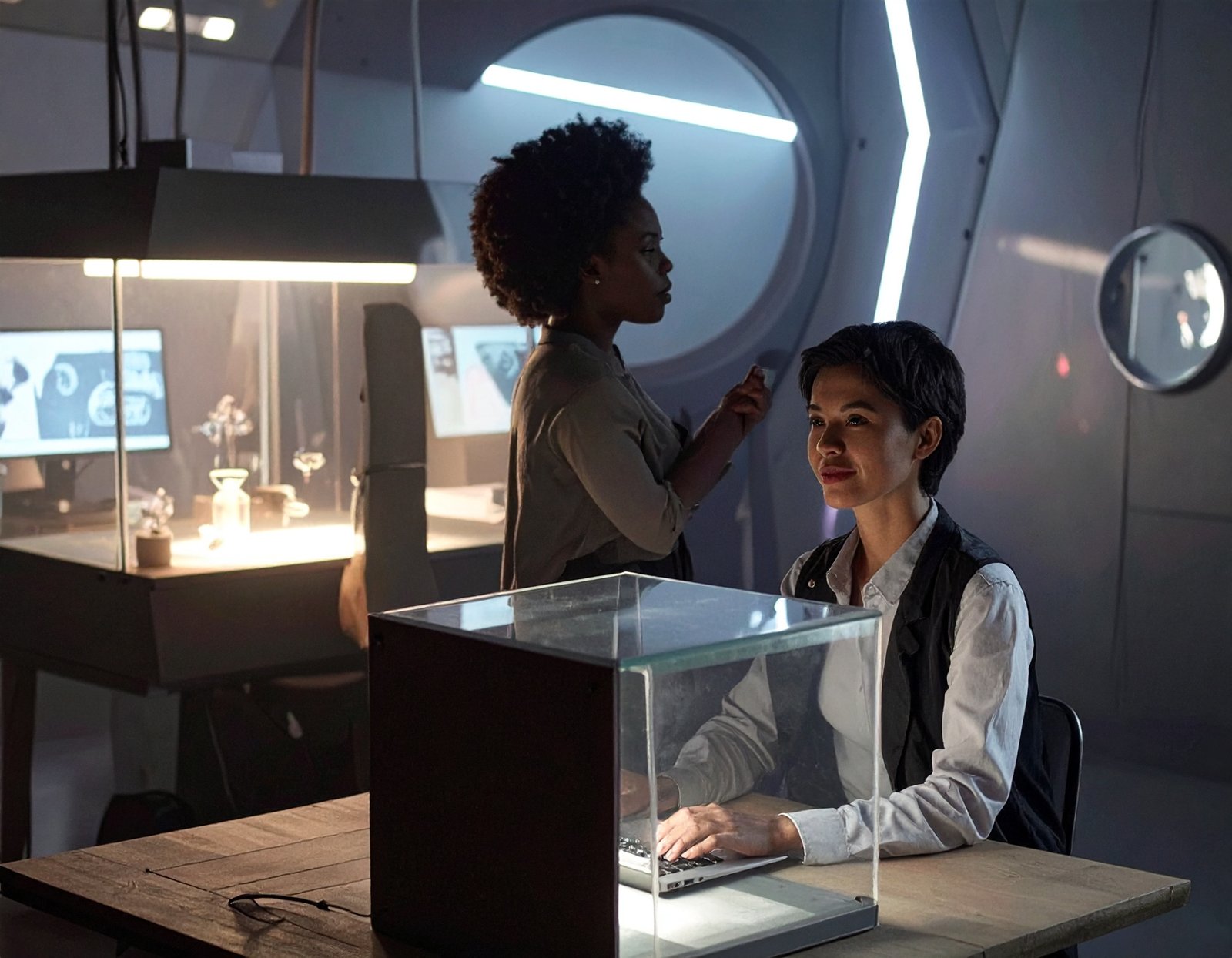 Non-designer careers - females sitting in a laboratory style studio with their hand sin glass cases to denote experimentation.