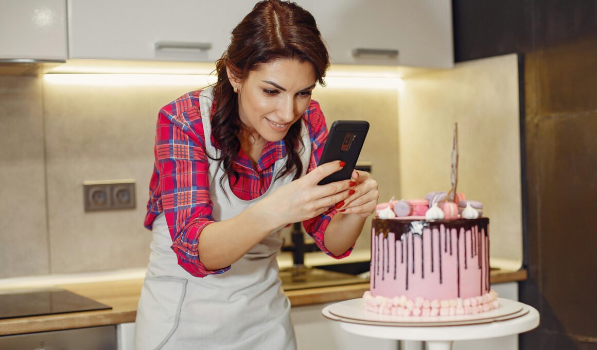 Feature image for the article: 'How to Know If Your Blog Idea Is Worth It (Before You Start)'. A young, white female, home baker, taking a photo of her decorated cake withe smart phone, kitchen in the background.