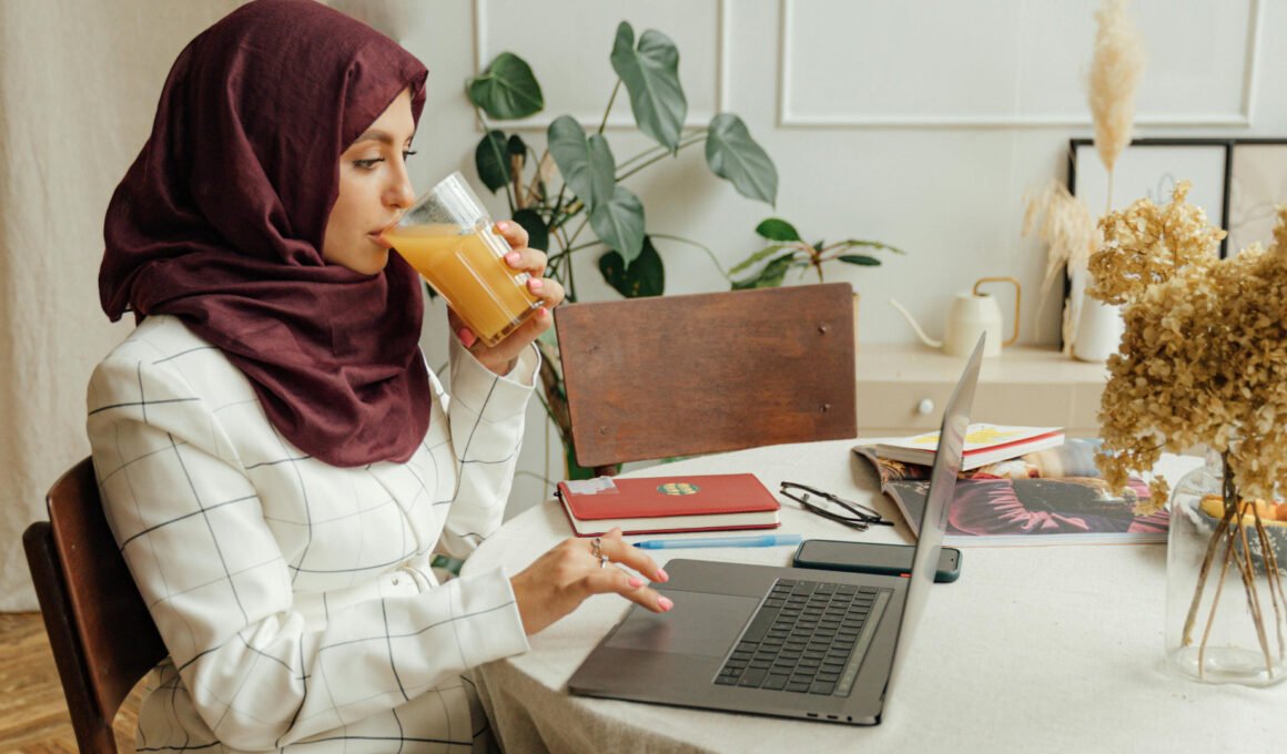Female Muslim blogger, typing calmly on her laptop while sipping orange juice - feature image for the article title: 'Do small niche blogs still make money 2026'
