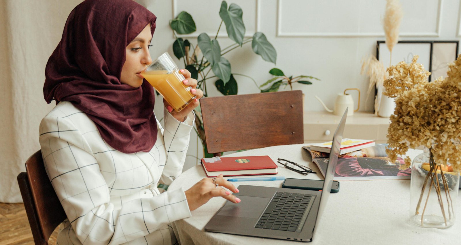 Female Muslim blogger, typing calmly on her laptop while sipping orange juice - feature image for the article title: 'Do small niche blogs still make money 2026'