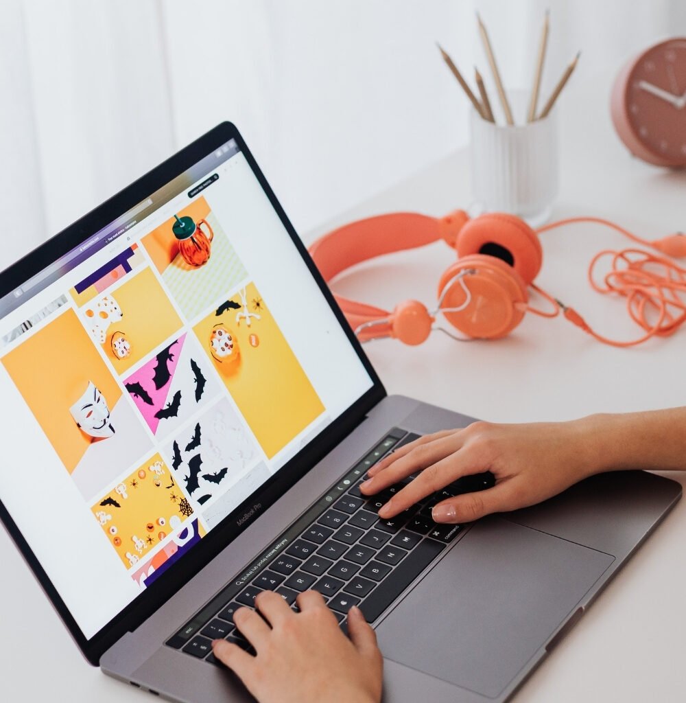 Blogger typing and designing graphics on a laptop for the article 10 Pinterest Pin Templates that actually get clicks.