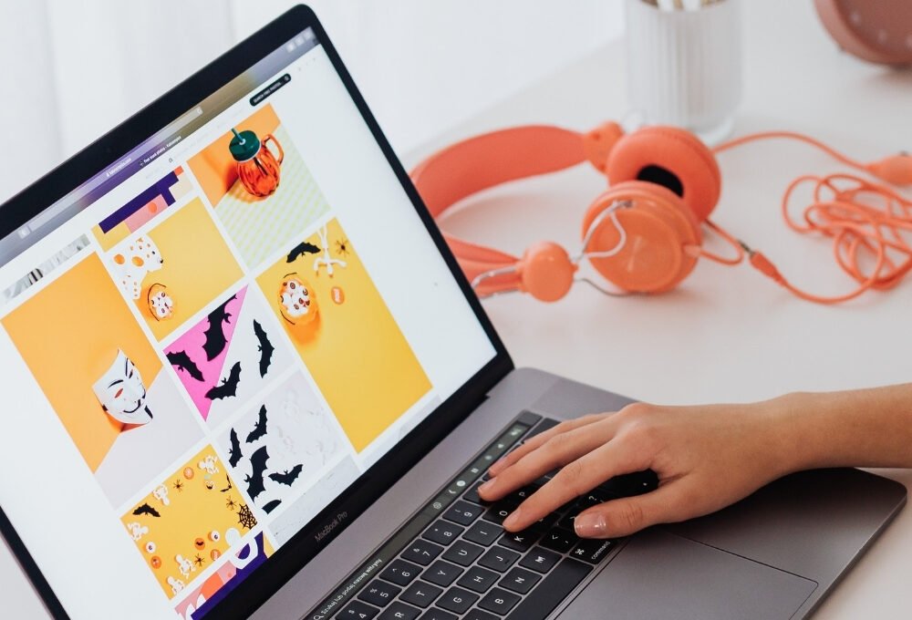 Blogger typing and designing graphics on a laptop for the article 10 Pinterest Pin Templates that actually get clicks.