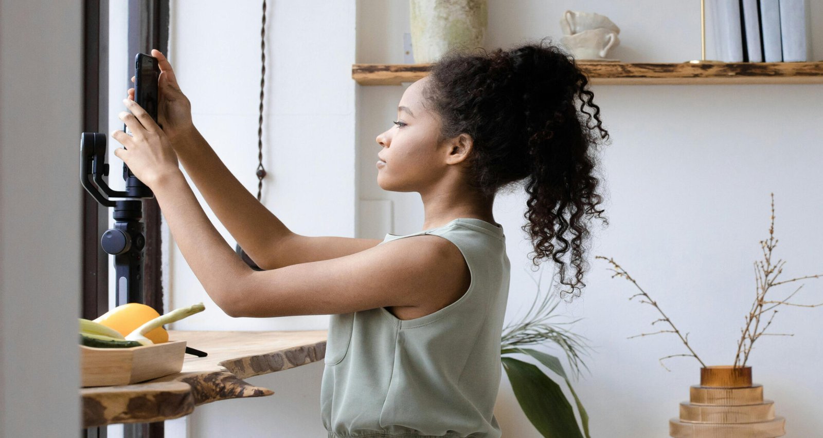 Young biracial or black female setting up her smart phone camera for content creation for article titled: How to Choose a Blog Niche When You Have Too Many Ideas