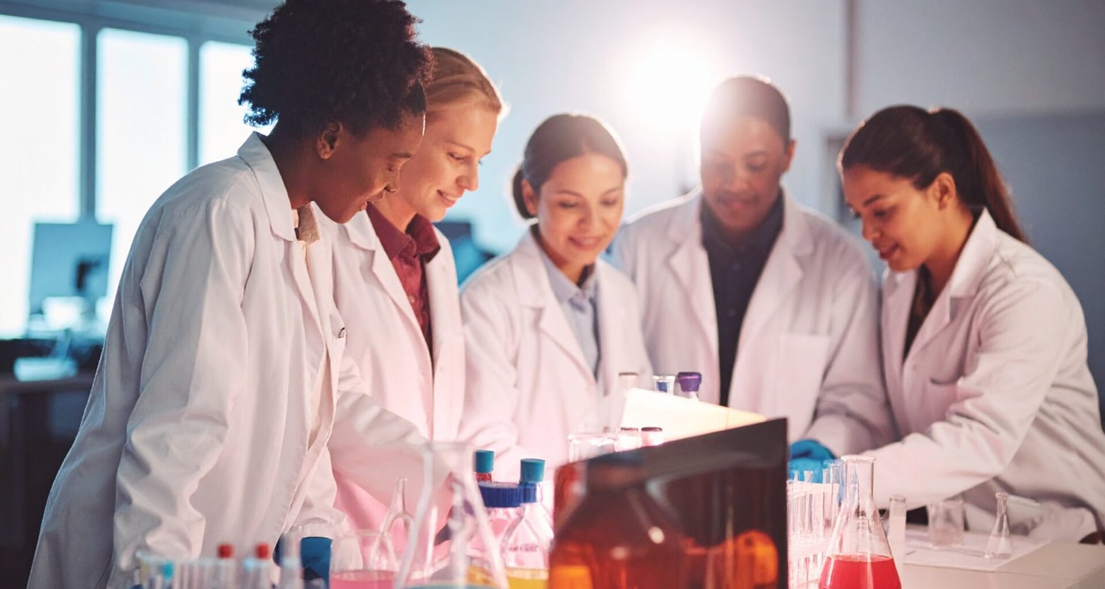Image of multiracial women in a laboratory in lab coats experimenting with formulas denoting experimenting with cooking and food content for the article 'How to Start a Profitable Recipe Blog in 2026 (The Stack I’d Actually Use)'