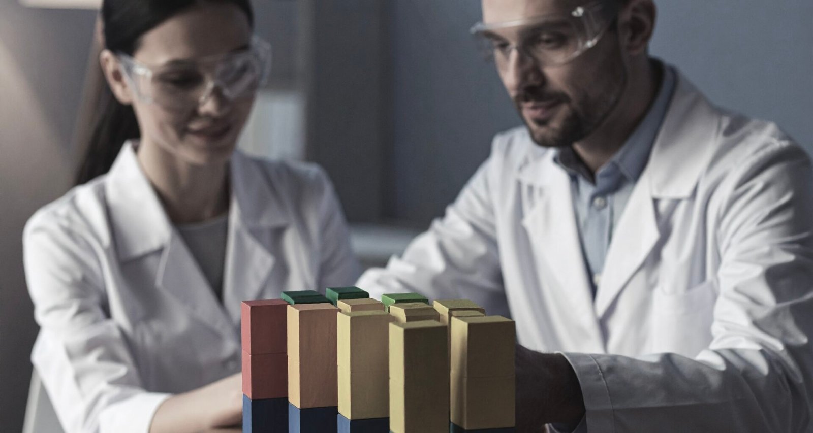 A man and a woman in lab coats in a laboratory looking at multicolour building blocks symbolising and testing blogging platforms - a feature image for the article titled Men and women in lab coats in a laboratory symbolising experimenting with blogging themes - a feature image for the article titled 'Recipe Sites – Best Platforms and Emerging Ones in 2026'