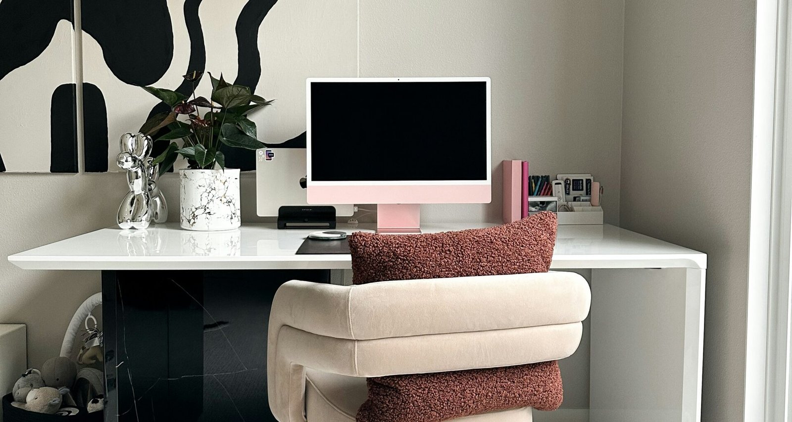 trendy desk with pink apple desktop screen and fashionable chair.